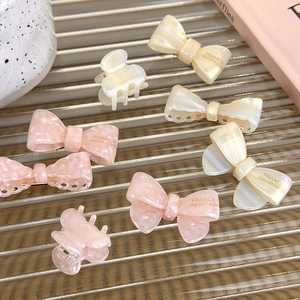 Detail of French handmade acetate hair clips with pink marble patterns and bow designs