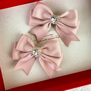 Close-up of pink satin bow hair clips with sparkling rhinestone heart centers