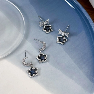 Detailaufnahme der Stern- und Mondohrringe mit dunkelblauen Glitzeranhängern und Schleifen