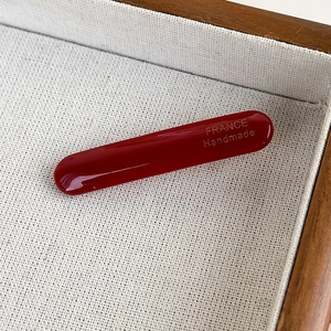 Detail of dark red acetate hair clip with gold France Handmade logo on fabric tray