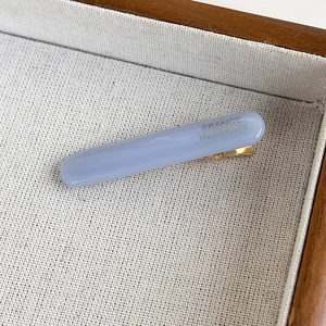 Close-up of a light blue acetate hair clip featuring a gold France Handmade inscription