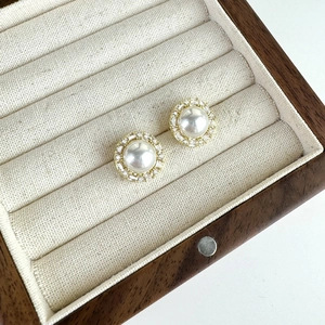 Vintage pearl stud earrings with zircon inlay in gold finish on wood jewelry box