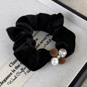 Detailed shot of a black velvet scrunchie featuring pearls, crystals, and flocked balls