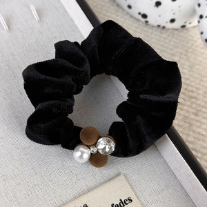 Close-up of velvet hair scrunchie with pearls, sparkling rhinestones and brown pom-poms
