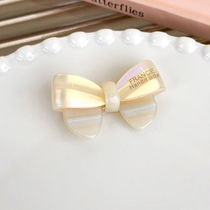Detail view of a pearlescent acetate bow hair clip with gold France Handmade logo
