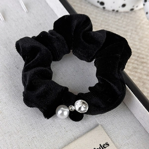Detailed shot of black velvet scrunchie with a white pearl and sparkling crystal gem