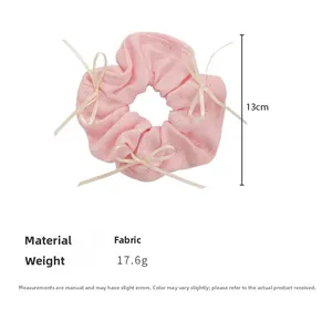 Détail d'un chouchou rose tricoté avec des nœuds blancs et un diamètre de 13 cm