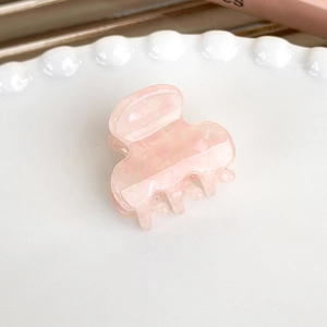 Macro shot of small pink jelly hair clip with marble texture on white plate
