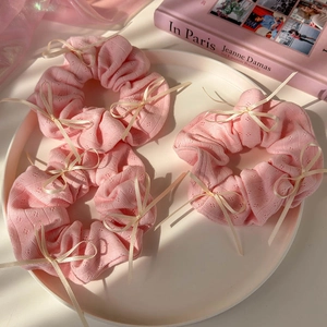 Lot de trois chouchous en tricot rose avec nœuds beiges sur un plateau blanc