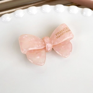 Close-up of pink marble acetate bow hair clip with gold France Handmade lettering