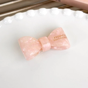 Detail of pink marble acetate bow hair clip with gold France Handmade lettering