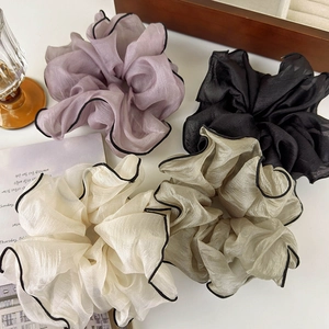 Detailed close-up of large chiffon scrunchies in four colors with black contrast stitching