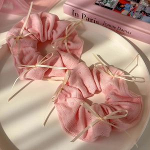 Lot de deux chouchous en tricot rose avec nœuds beiges sur un plateau décoratif