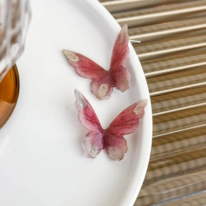 Detail of butterfly stud earrings with pink gradient resin and sparkling glitter finish