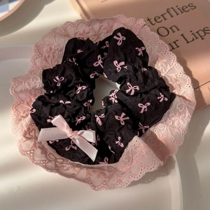 Detail of a black lace hair scrunchie with pink bows and 3D ribbon decoration on tray