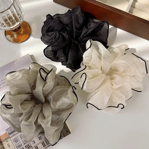 Close-up of oversized organza hair scrunchies with black edges in beige and pink tones