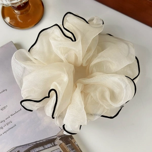 Close-up of ivory organza scrunchie with black wave edge stitching and pleated texture