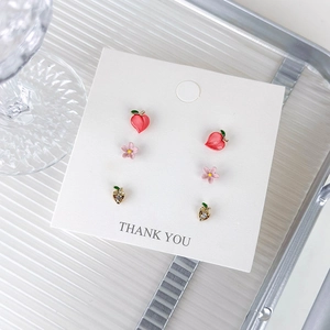 Detail of sweet earring set with pink cherry blossoms and red peach heart studs