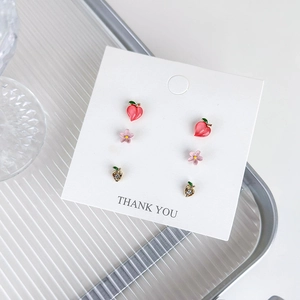 Detailed set of three pink cherry and flower earrings displayed on a clean white card