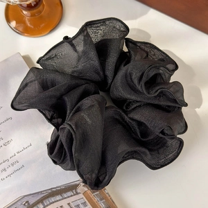 Macro view of oversized black chiffon hair scrunchie with sheer texture and glossy edges