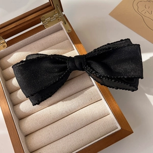 Gros plan détaillé de la barrette à cheveux en tulle noir multicouche à bords ondulés