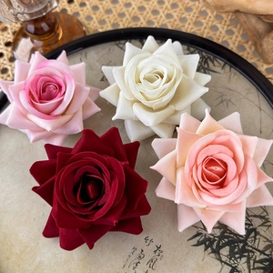 Realistic artificial rose flower hair clips in four vintage colors on a decorative tray