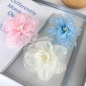 Detalle de horquillas de flores de tul hechas a mano en rosa, azul y crema sobre una bandeja