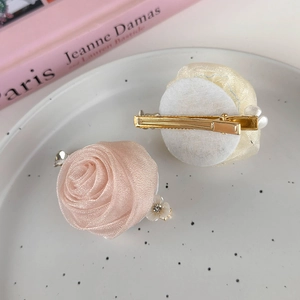Detailed macro view of handmade mesh rose hair clips with delicate pearls and gold metal base