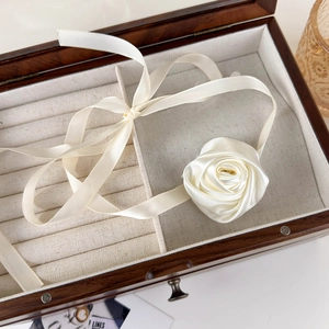 Macro view of creamy white satin rose choker featuring silky ribbon textures and French style
