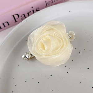 Detailed macro of cream organza rose hair clip with sparkling rhinestones and floral accents
