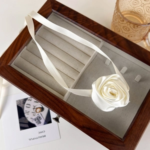 Detailed view of elegant cream satin rose ribbon necklace on a vintage jewelry box setup