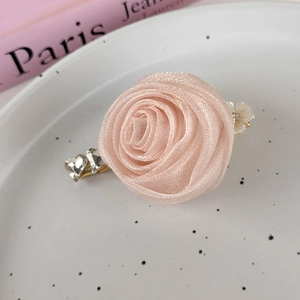 Detail view of handmade pink organza rose hair clip with heart crystals on white plate