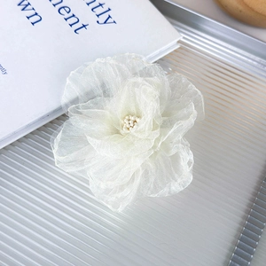Detalle de la pinza para el pelo con flor de gasa marfil y perla sobre una bandeja