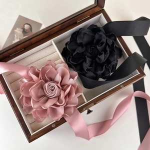 Détail de chokers fleurs en tissu rose et noir avec rubans de soie dans une boîte en bois
