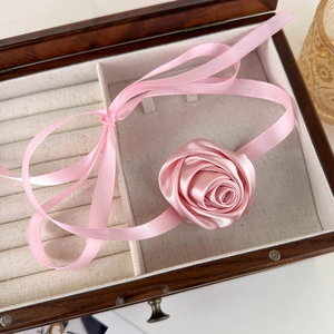 Macro view of a 3D pink satin rose flower choker with long adjustable silk ribbons