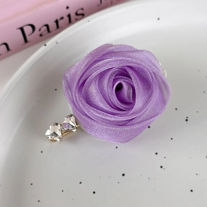 Detail of a purple mesh fabric rose hair clip featuring clear heart-shaped rhinestones