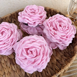 Detailed view of layered fabric rose hair clips in soft pink inside a woven basket