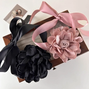 Détails d'accessoires de cheveux en fleurs de soie noir et rose sur boîte en bois