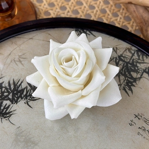 Macro shot of 3D layered cream fabric rose hairpin with realistic textile texture