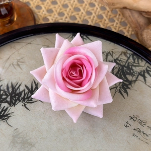 Detailed view of a pink gradient artificial rose hair clip with velvety petals texture