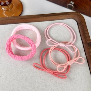 Dettaglio di un set di quattro elastici per capelli rosa con fiocchi e anelli in spugna