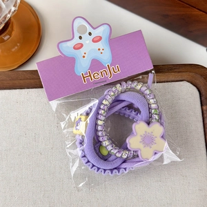 Close-up of a purple floral scrunchie set and flower elastic hair ties on wood