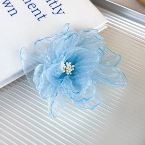 Detalle de pinza para el pelo con flor de organza azul claro y estambres blancos