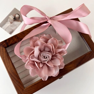 Détail d'une grande fleur en tissu rose avec des rubans de satin sur un coffret à bijoux