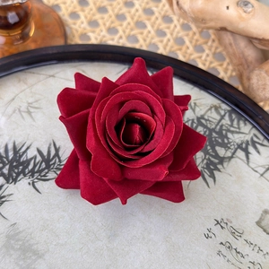 Macro view of deep red velvet rose hair clip showing realistic petals and texture