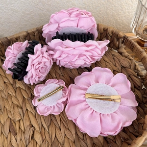 Detailed view of dried rose fabric hair clips and shark clips in a woven basket