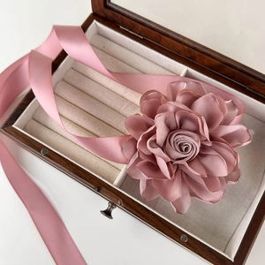 Détail d'une fleur en satin rose avec de longs rubans pour la coiffure ou le cou