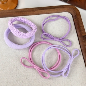 Dettaglio di elastici per capelli color pastello con fiocchi su vassoio di legno