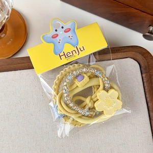 Detailed view of yellow hair elastic set with floral pendant and star-patterned carding