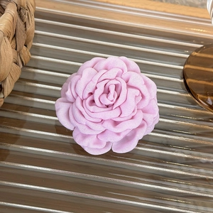 Detailed view of handmade pink fabric rose hair claw clip on a warm glass surface